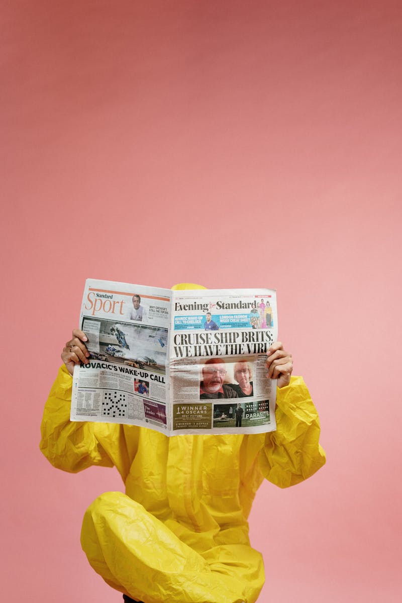 Person in Yellow Coveralls Reading Newspaper