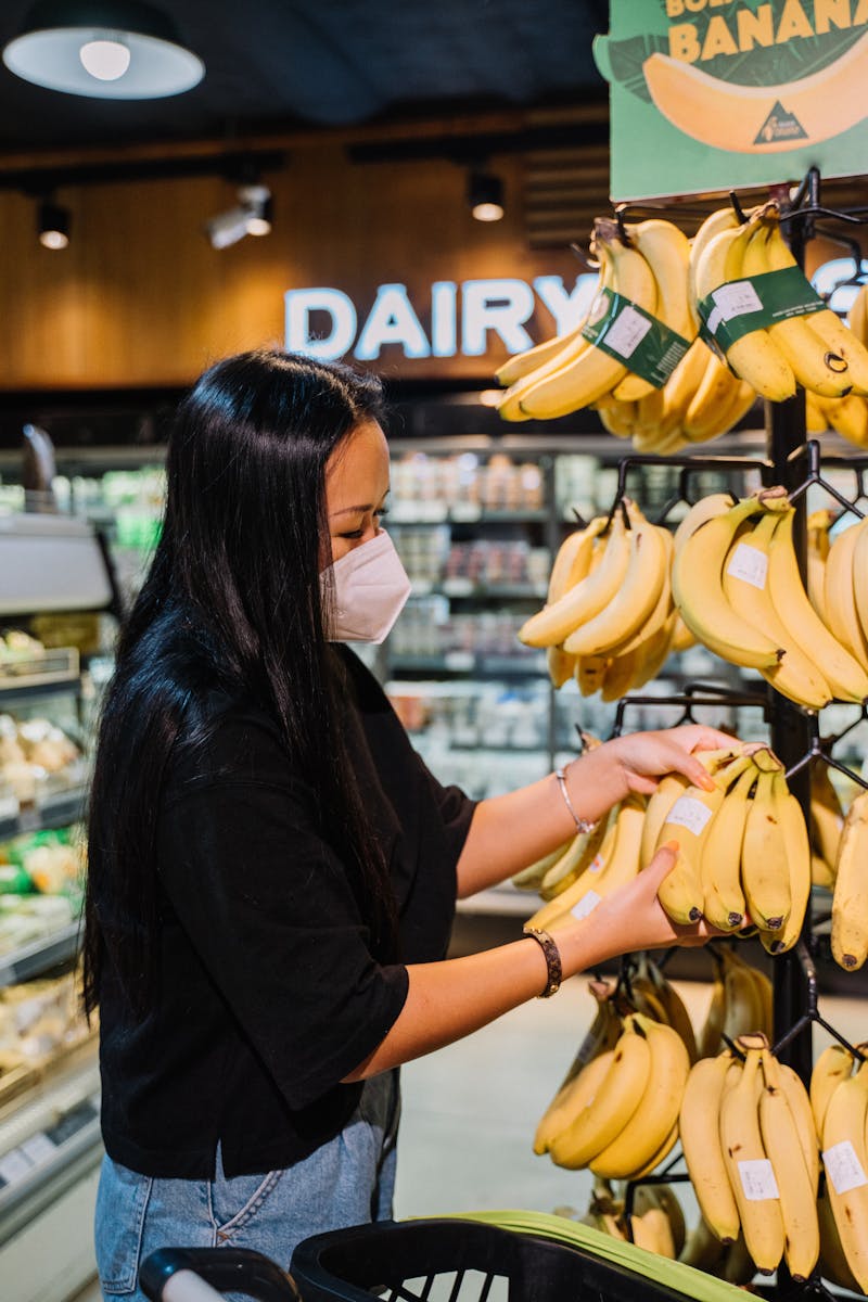 Woman With Face Mask Holding Yellow Bananas