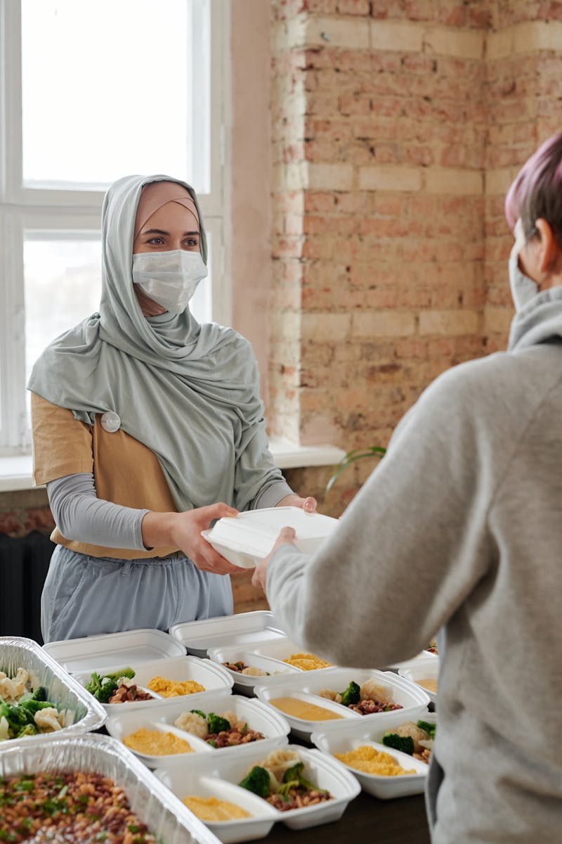 A Woman in Hijab Giving Out a Packed Food