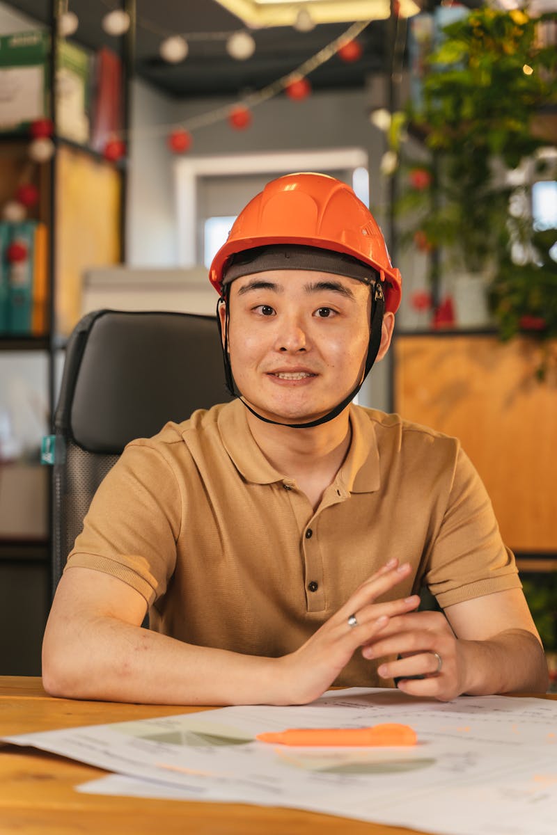 Man Wearing a Hard Hat Sitting in Front of a Desk