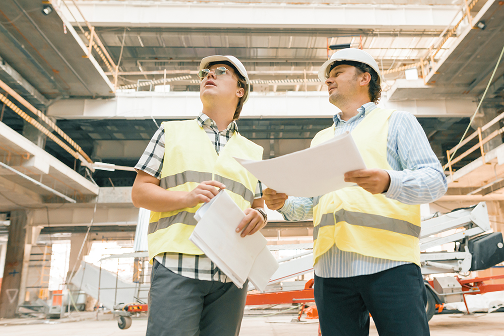Male construction inspector examining construction site. Building, development, teamwork and people concept.