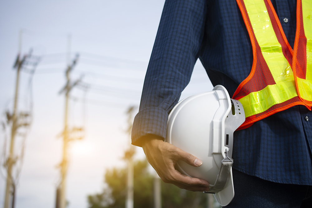 Engineering holds white safety hats and electric pole background